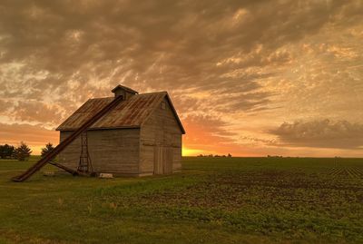 House on field against sky during sunset