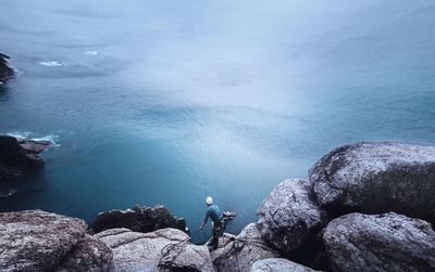 High angle view of of man rock climbing by sea