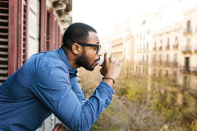 Young man on balcony drinking coffee