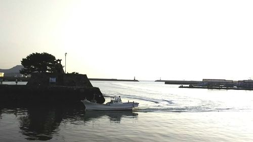 Boats in calm sea against clear sky