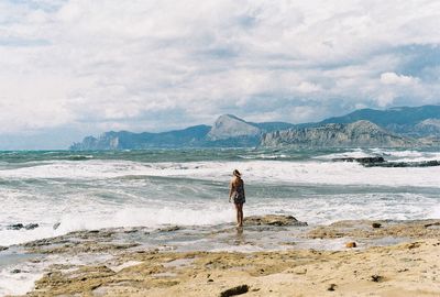 Woman standing on beach against sky