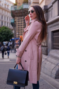 Side view of young woman standing on footpath