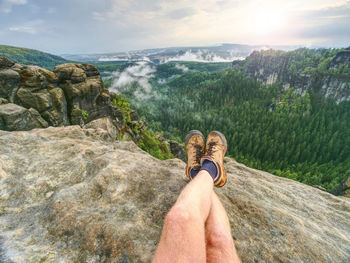 Nature with detail hiker legs in black orange leather boots on mountain. feets in low trekking soes