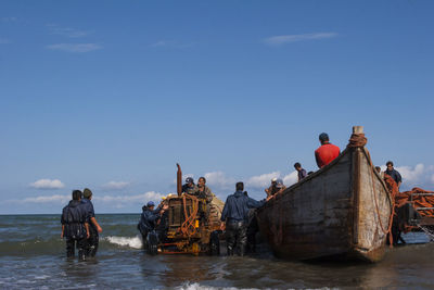 People on boat in sea against clear blue sky