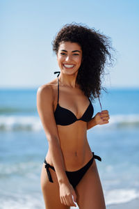Portrait of smiling sensuous young woman wearing bikini at beach