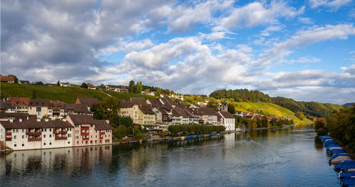 Buildings by river against sky in town