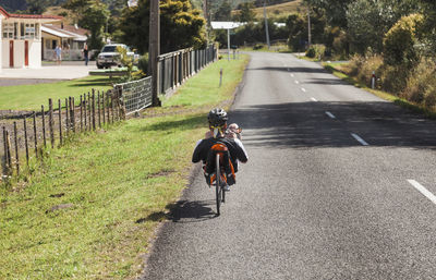 Rear view of man riding bicycle on road