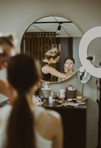 A young makeup artist applies protective cream to a girl s face.