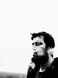 Portrait of young man looking away against sky