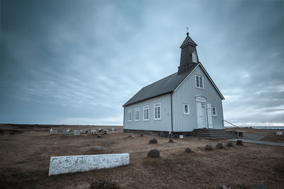 Church by cemetery against cloudy sky