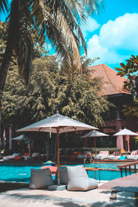 Chairs by swimming pool against sky