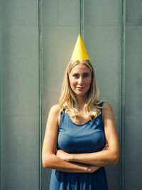 Portrait of a smiling young woman standing against wall