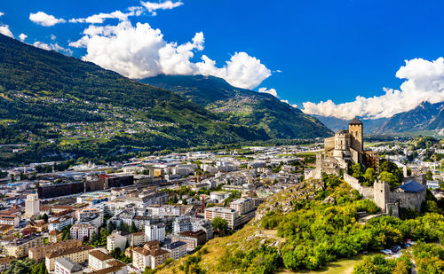 Aerial view of townscape and mountains against sky