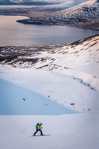 Man backcountry skiing with water and ocean behind in iceland