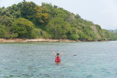 Man kayaking in sea against trees