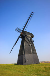 Traditional windmill on field against clear sky