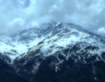 Scenic view of snow covered mountains against cloudy sky