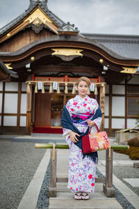 Portrait of woman standing against building