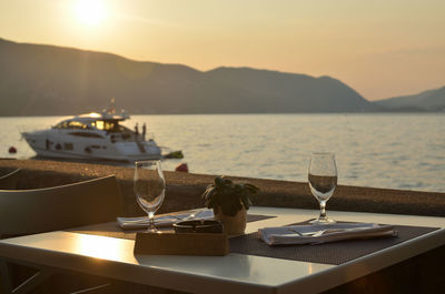 Empty wine glasses on a seashore restaurant table, with a reservation sign-and a boat on sea