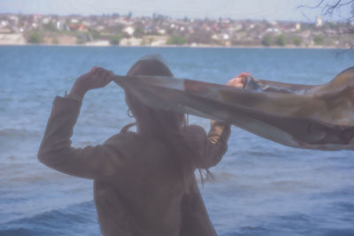Rear view of woman hand against sea