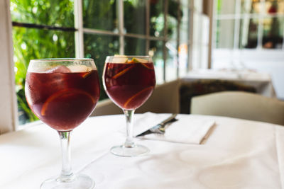 Two sangria wine glasses with slices of oranges against blurry background in a restaurant