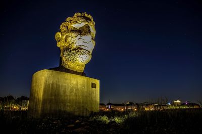 Low angle view of statue against illuminated building at night