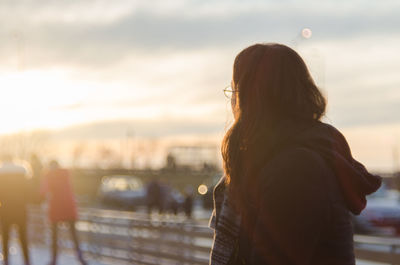 Rear view of woman standing by railing against sky