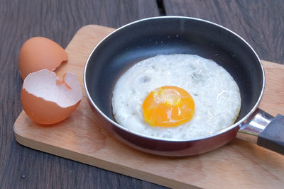 High angle view of egg in cooking pan on cutting board