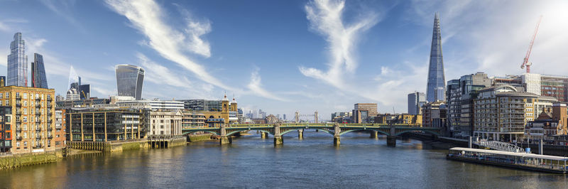 Bridge over river by buildings against sky