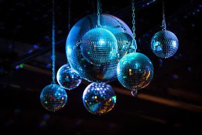 Low angle view of illuminated lighting equipment hanging at night