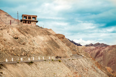 A historic broken house on the road amidst mountain against sky