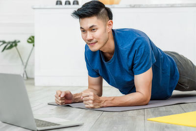 Man exercising while looking at laptop at home