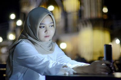 Portrait of young woman using mobile phone at home