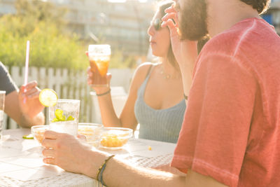 Midsection of woman drinking glass on table