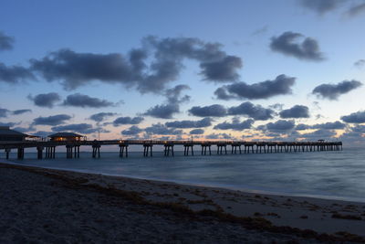 Pier over sea against sky during sunset