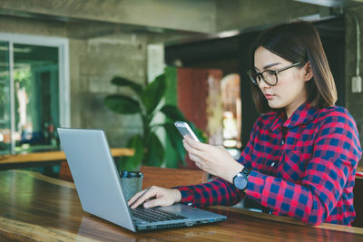 Woman using phone while sitting on table