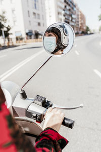 Reflection of man photographing on side-view mirror