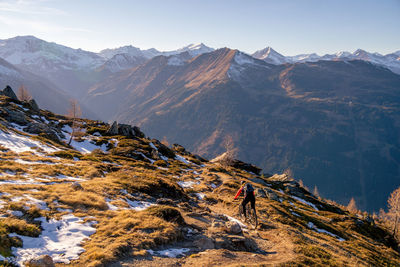 Woman riding a mountain bike on footpath in snow covered alpine terrain, gastein, salzburg, austria.