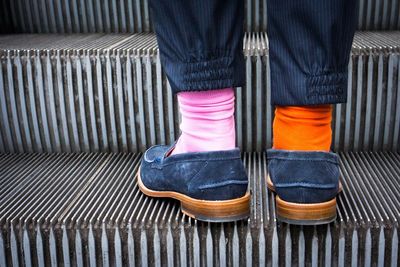 Midsection of a person wearing two different socks on escalator