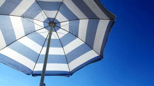 Low angle view of umbrella against clear blue sky