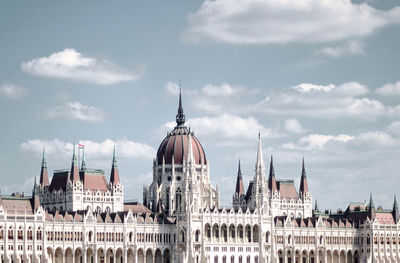 Buildings in city against cloudy sky