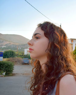 Side view of thoughtful young woman standing against clear sky