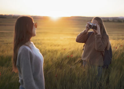 Two women holding hands at sunset in the field