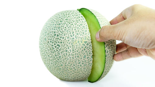 Close-up of hand holding ball over white background