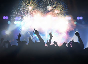 Rear view of people enjoying firework display at night