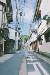 Woman on road amidst buildings in city