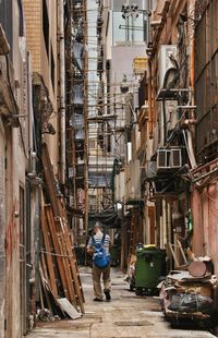 Man walking along clattered back alley