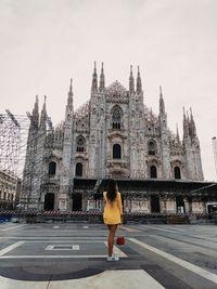 Rear view of woman standing outside temple against building