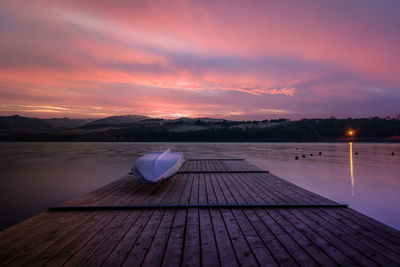 Pier over lake against sky at sunset