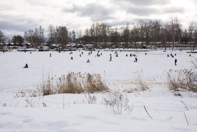 View of people on snow covered field against sky